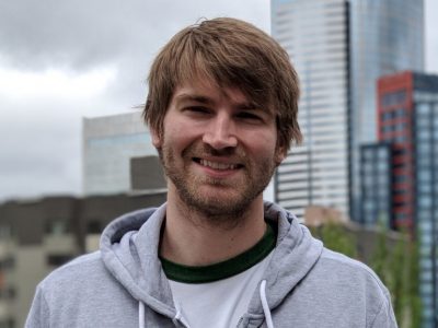 Photo of a man in a hooded sweatshirt against the Seattle skyline