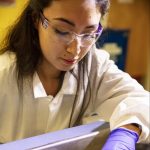 Image of a woman in a laboratory wearing gloves and protective goggles