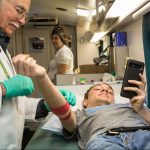 Image of a male phlebotomist helping a female high school student give blood